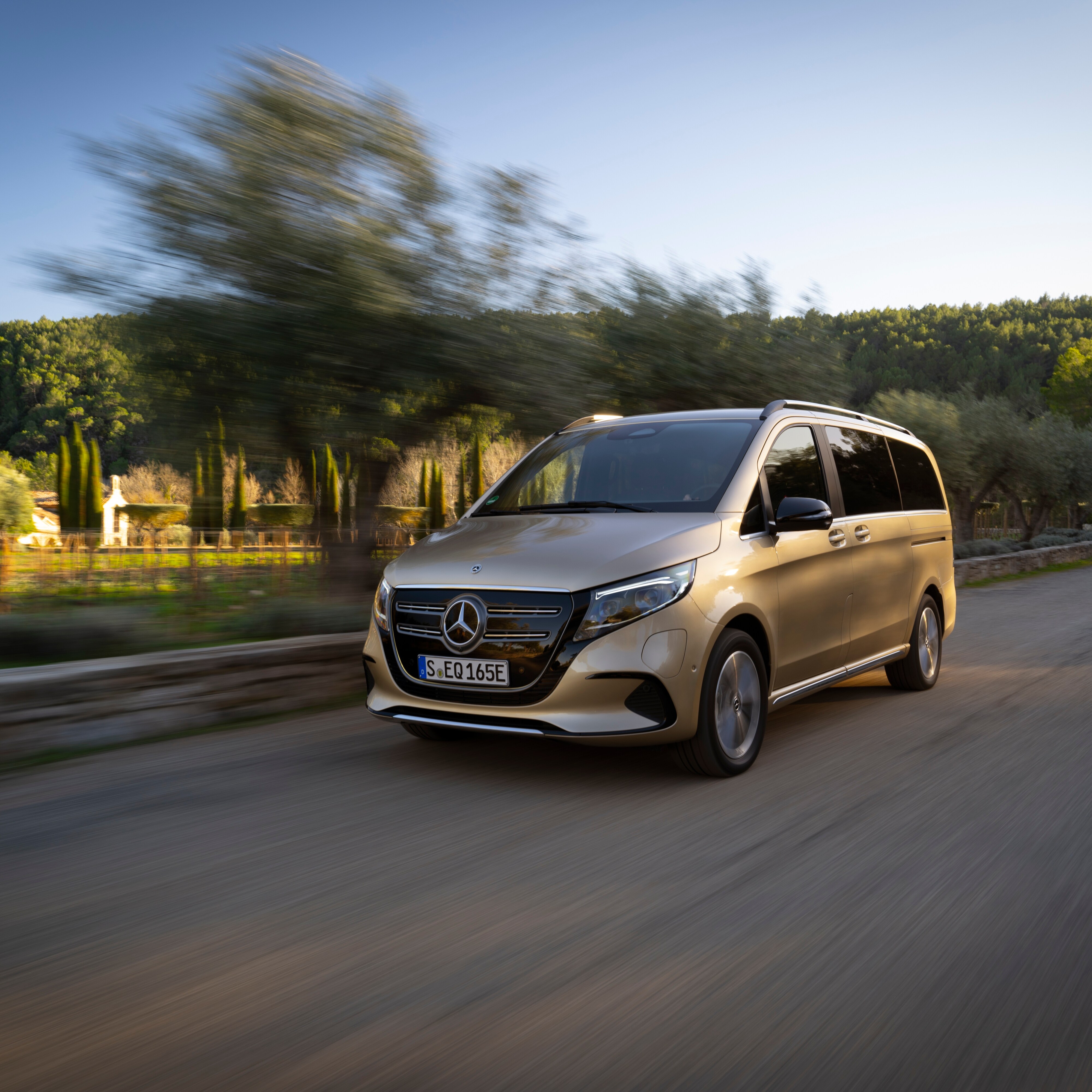 The image shows the Mercedes-Benz EQV driving on a road. 