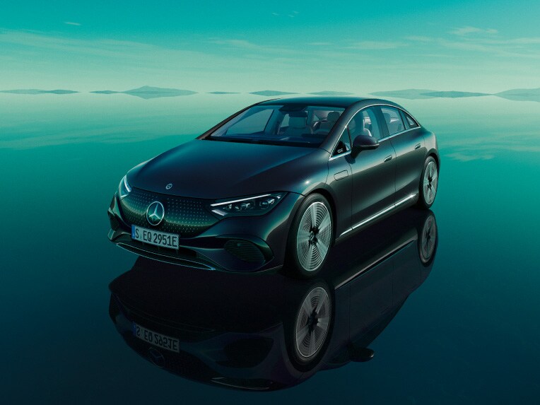 The all-electric EQE from Mercedes-EQ standing in its green EQ world with a mirroring floor surface.