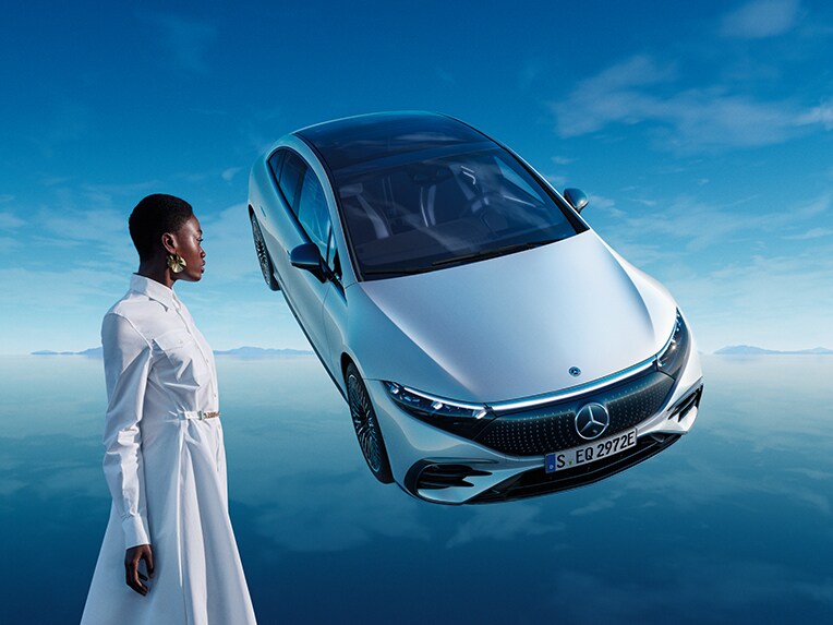 The all-electric EQS from Mercedes-EQ standing in its blue EQ World with mirroring floor surface.