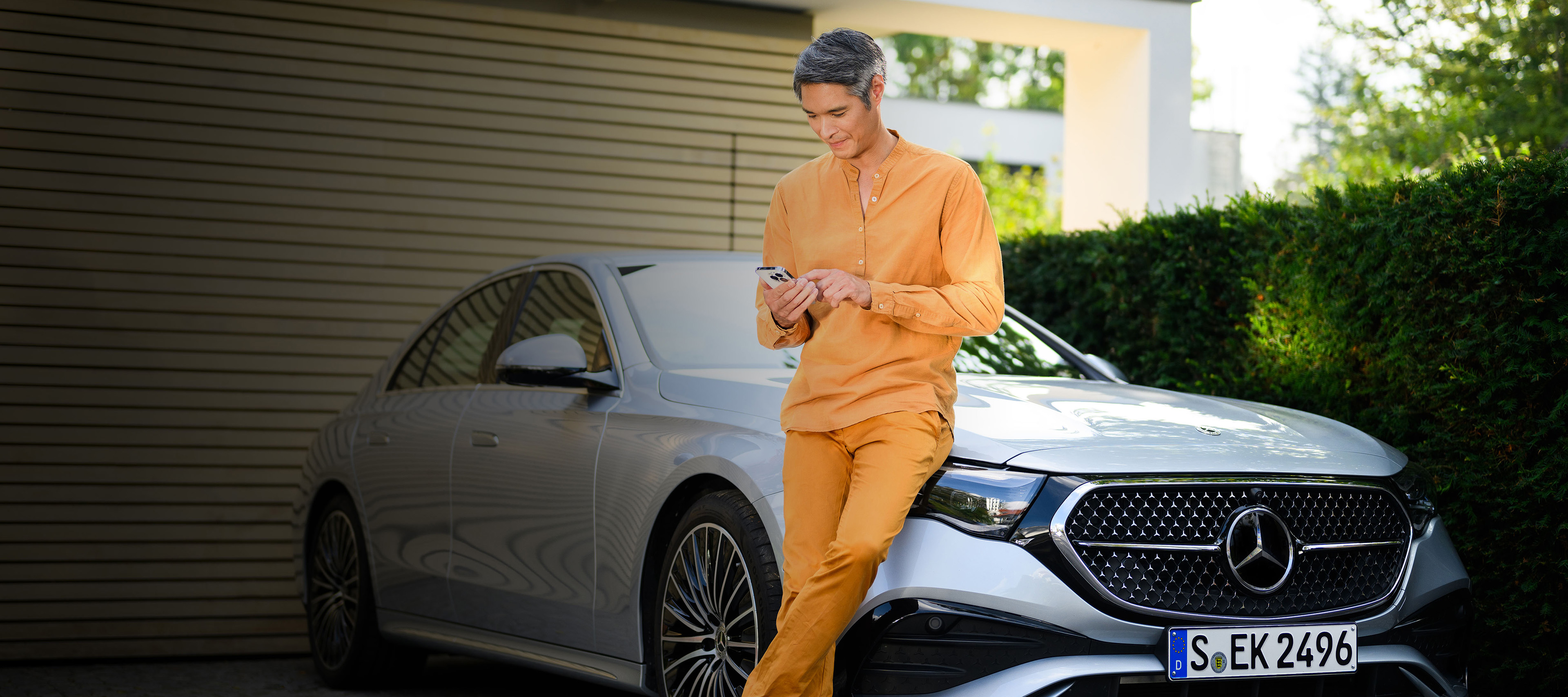 Financing offers for your Mercedes-Benz A person leaning against a Mercedes-Benz vehicle, using a mobile device.
