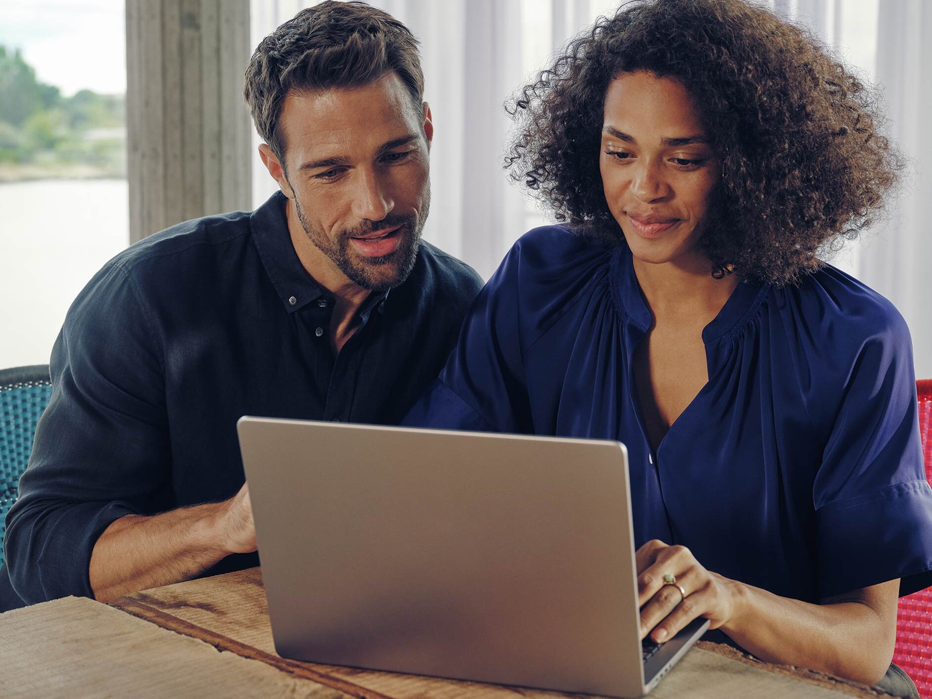 Man and woman seated at a desk looking at a laptop