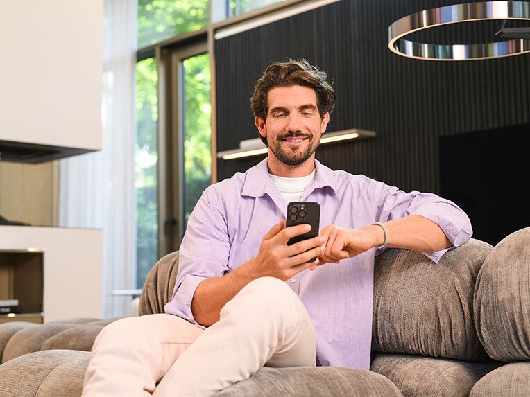 A person sitting on a sofa and using their mobile device.