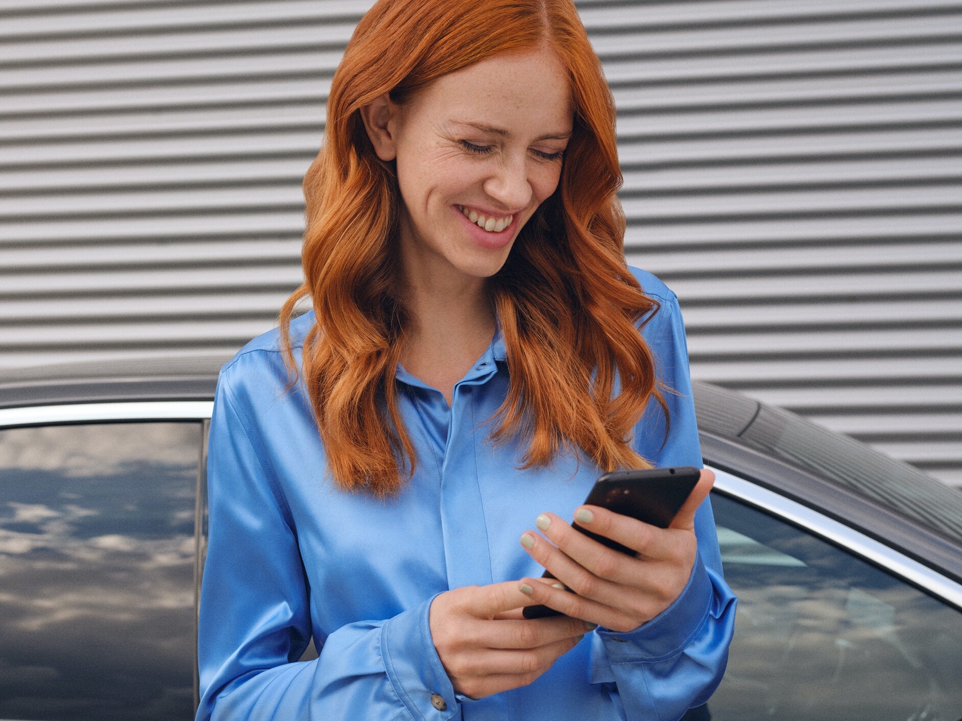 A woman connects to her Mercedes-Benz via the Mercedes me App on her smartphone.