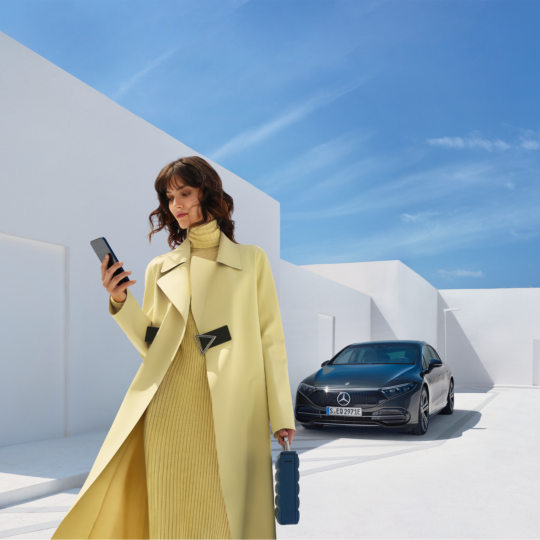 Buy Digital Extras | Entertainment | Mercedes-Benz Woman looking at her cell phone as she walks away from her Mercedes-Benz with EQ technology.