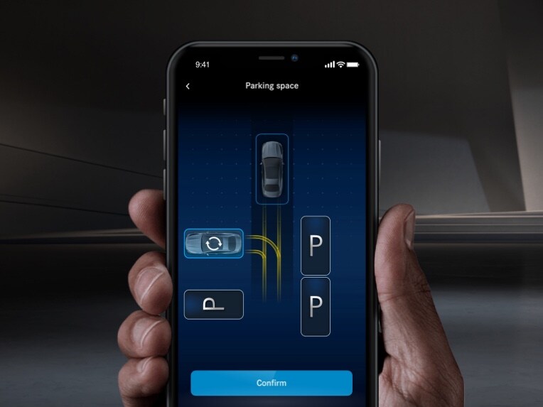 A smartphone is used to park a Mercedes-Benz using the Mercedes me Remote Parking App.