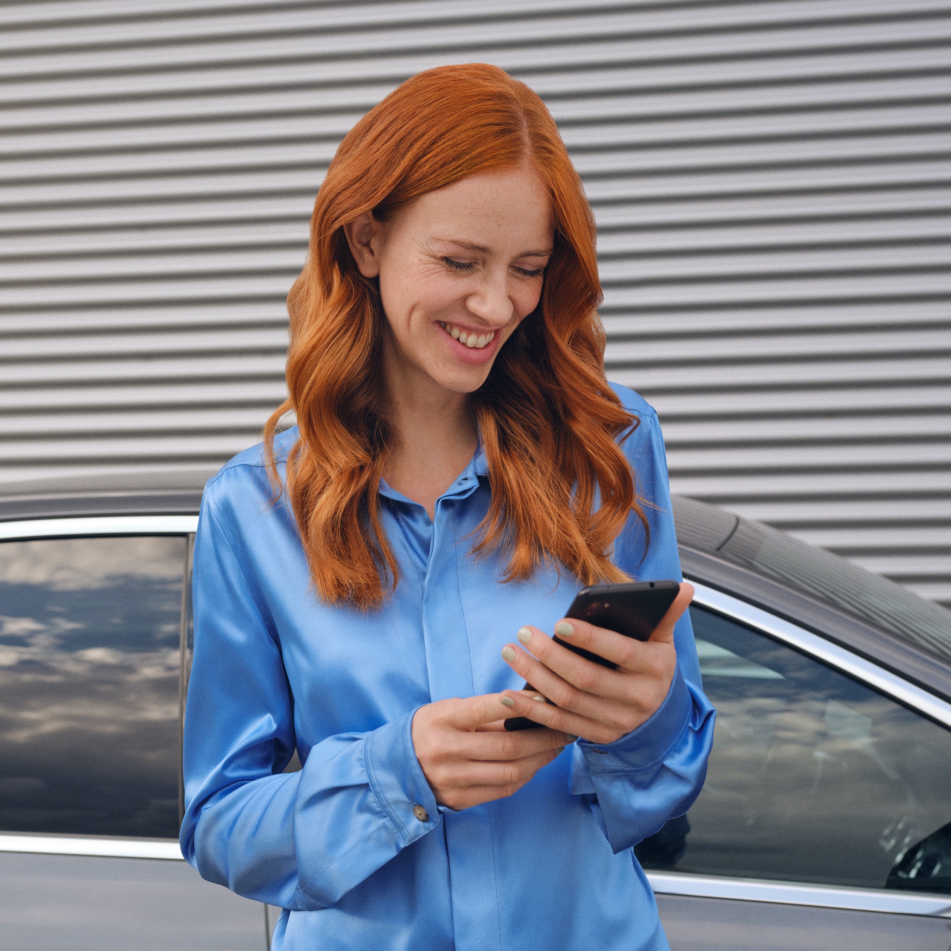 A woman connects to her Mercedes-Benz via the Mercedes me App on her smartphone. A woman connects to her Mercedes-Benz via the Mercedes me App on her smartphone.