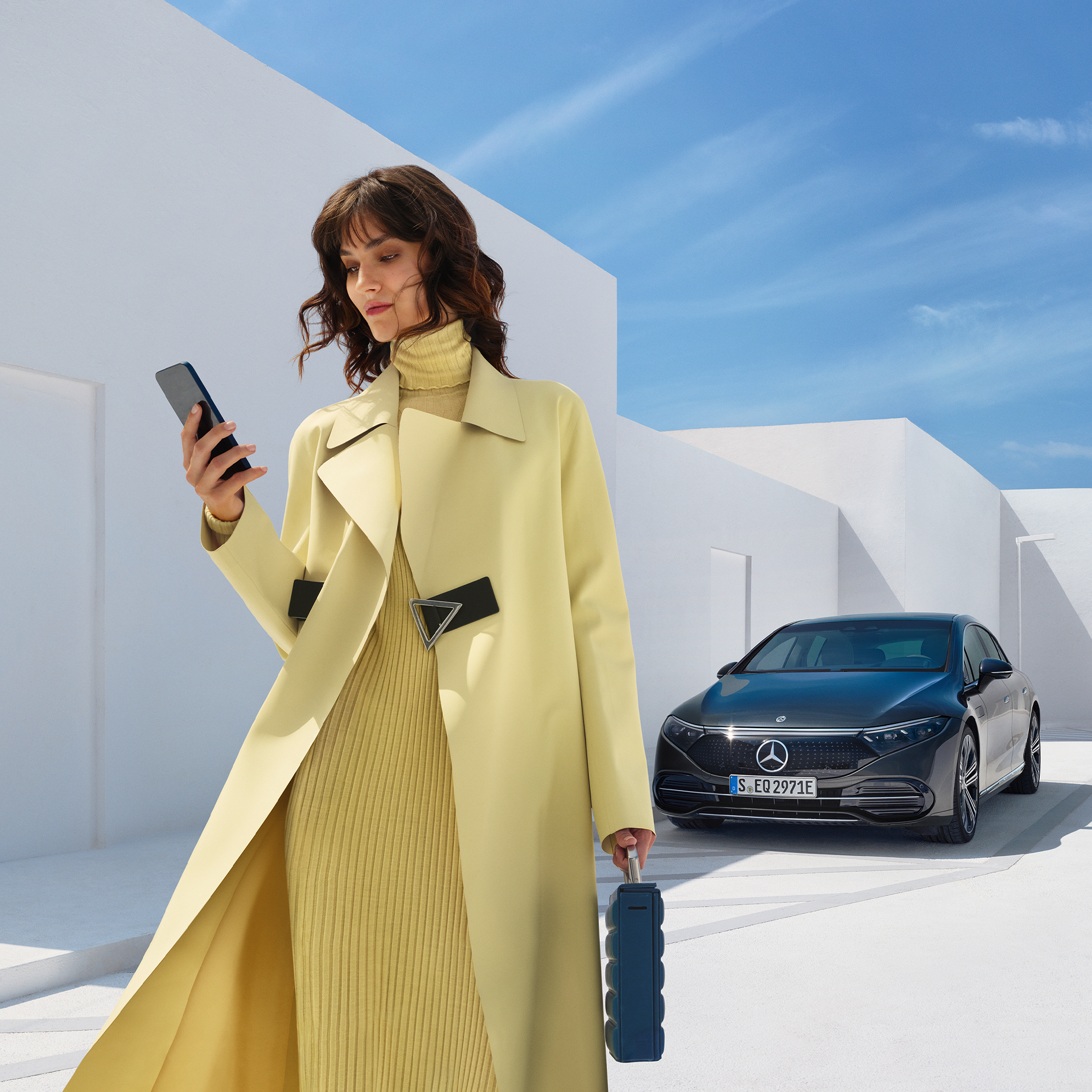 Buy Digital Extras | Remote | Mercedes-Benz A woman standing in front of the EQS Saloon from Mercedes-Benz.