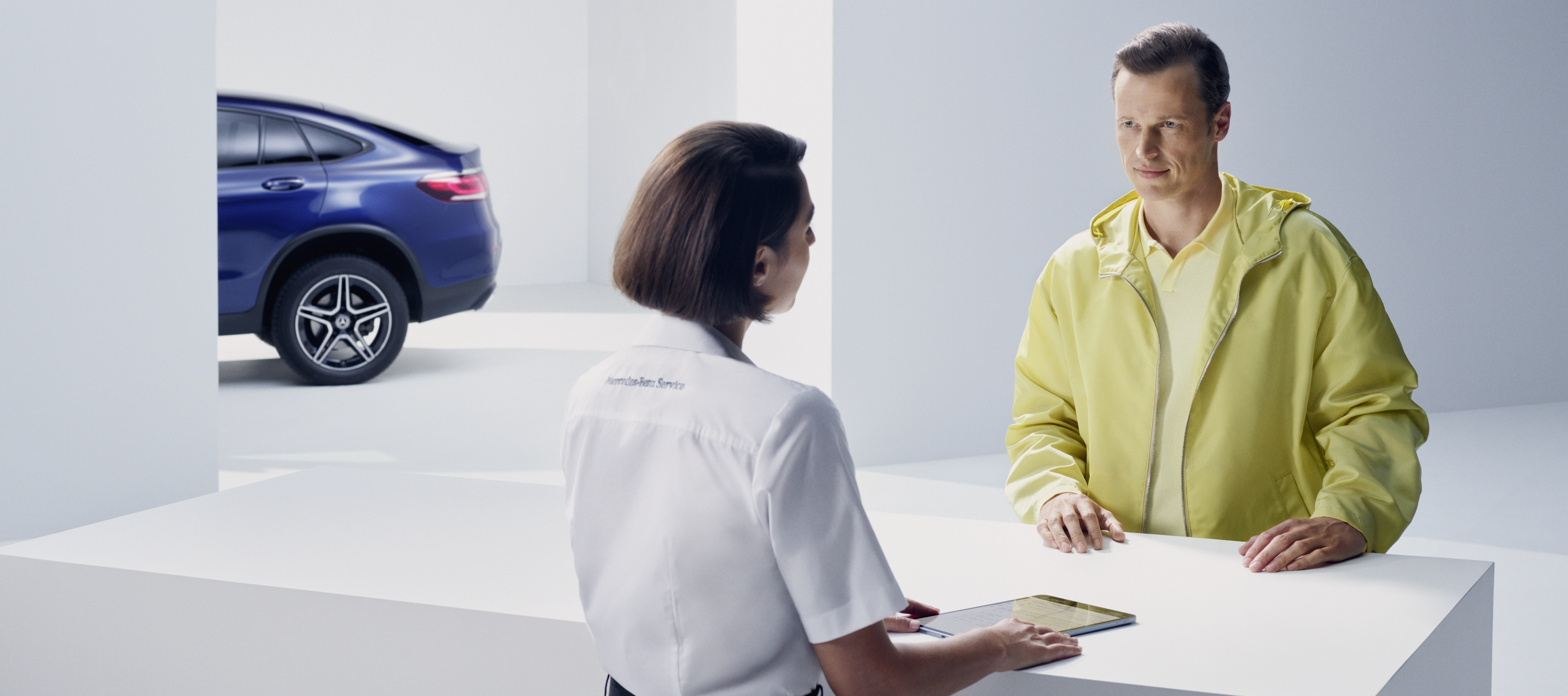 Mercedes-Benz Recall | Mercedes-Benz A customer leaning at the counter turns expectantly to face a Mercedes-Benz employee.