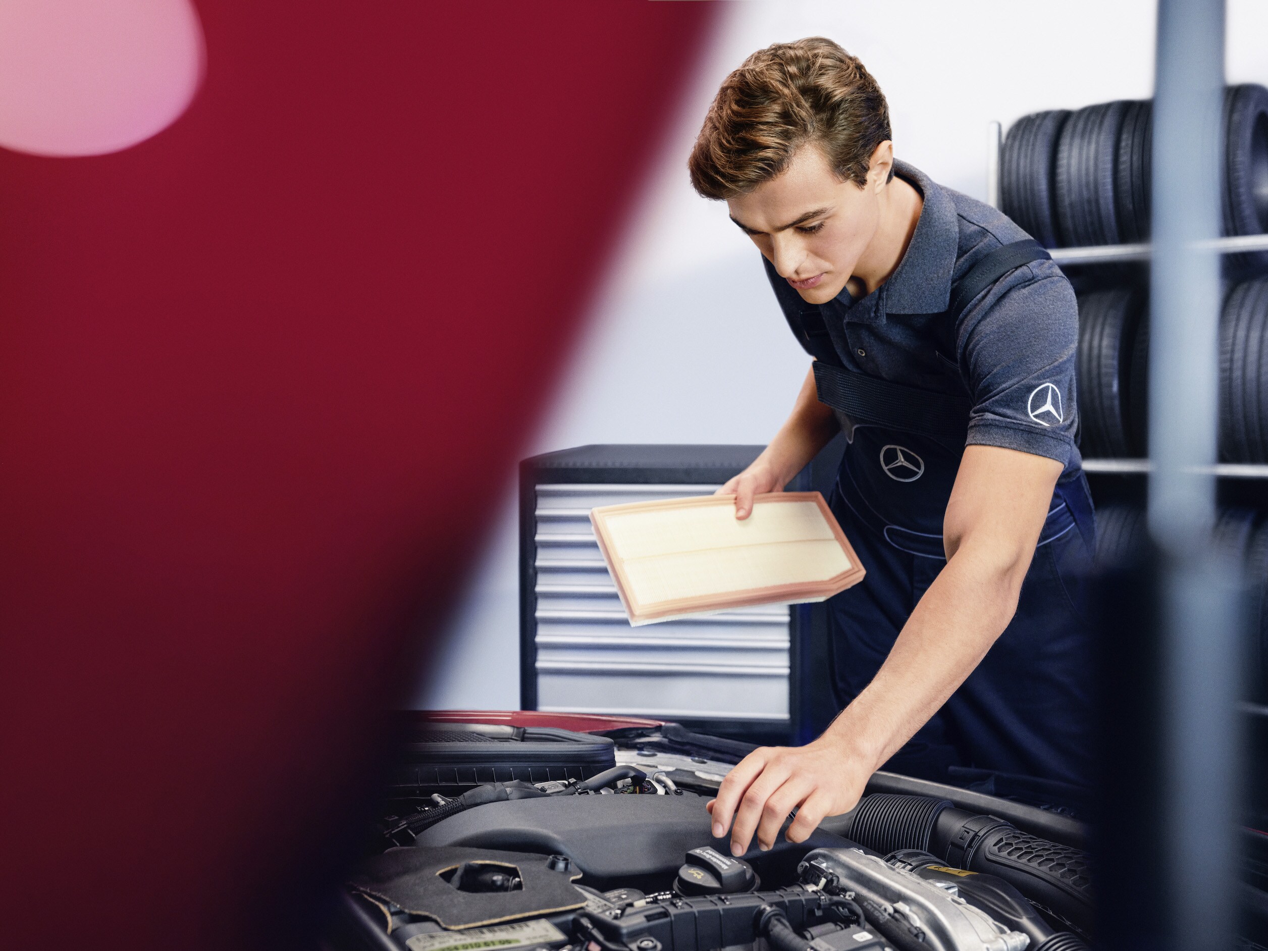 A Mercedes-Benz technician checks the engine compartment of a vehicle.