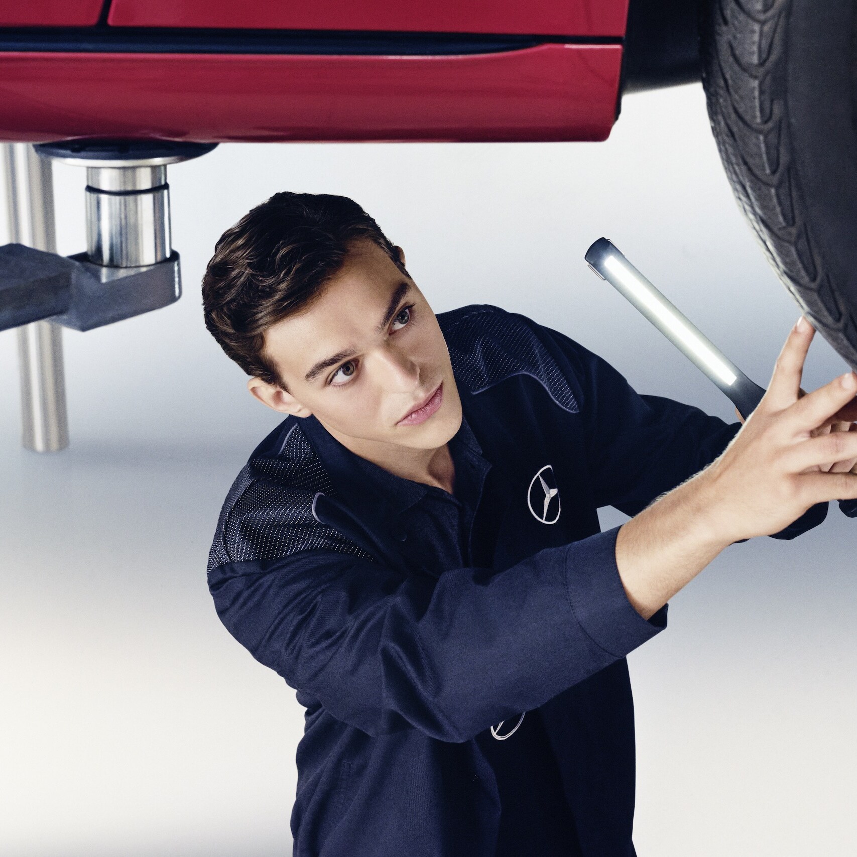 A Mercedes-Benz mechanic examines the wheel of a Mercedes-Benz.