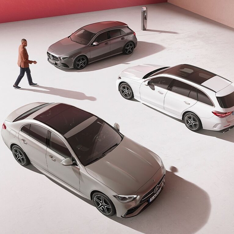 A man and woman in between different passenger car models from Mercedes-Benz