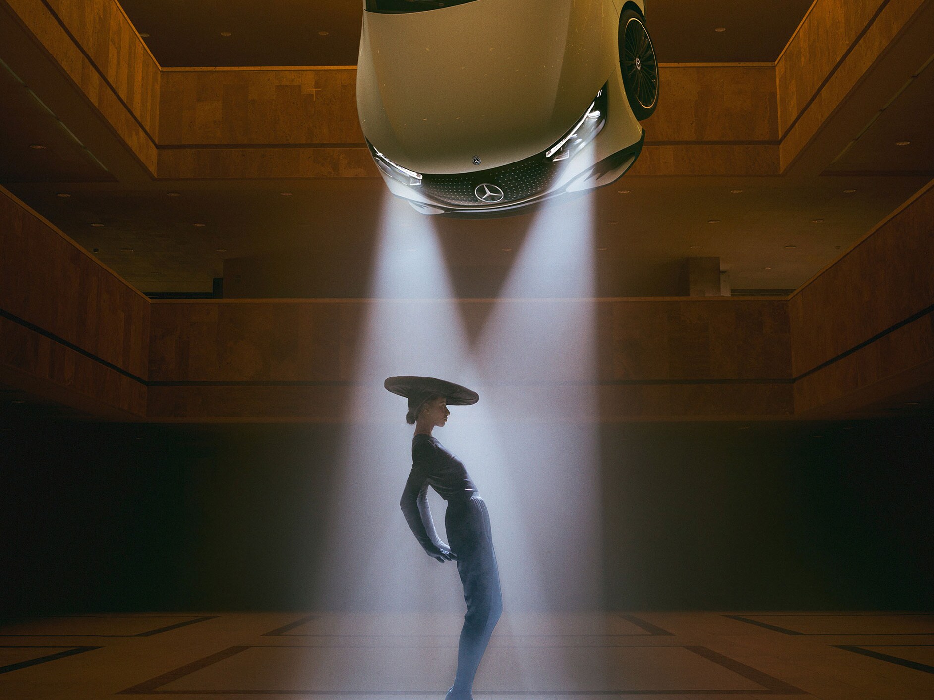 A dancing person in the headlights of an floating car by Mercedes-Benz.