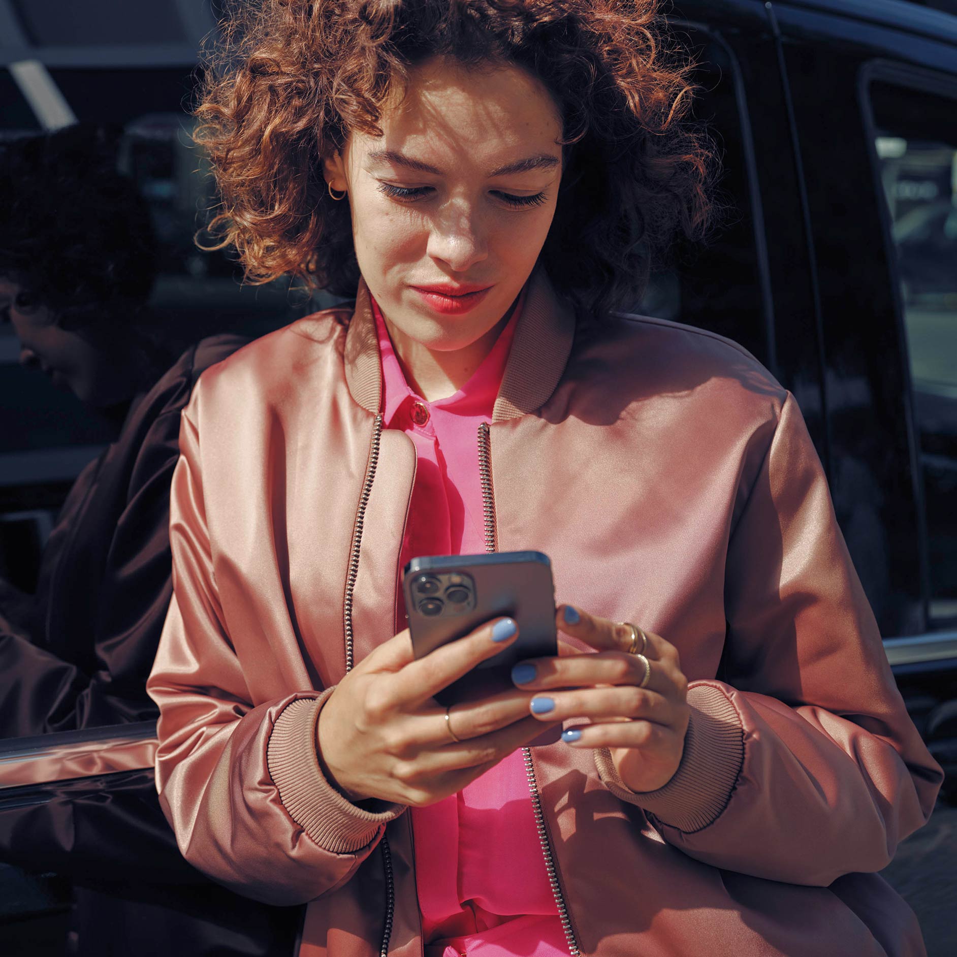Rent | Financial Services | Mercedes-Benz Vans A woman on the phone next to a black Mercedes-Benz EQV van