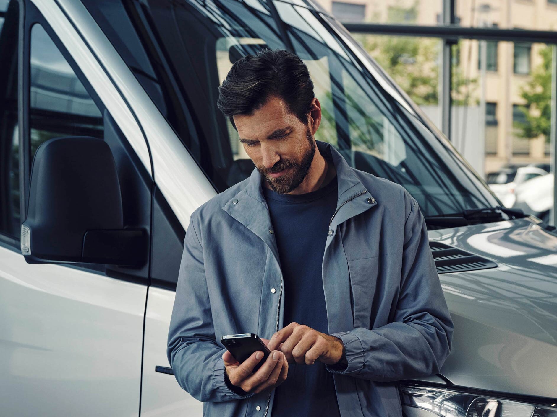 A man standing next to a white Mercedes-Benz eSprinter Van talking on the phone
