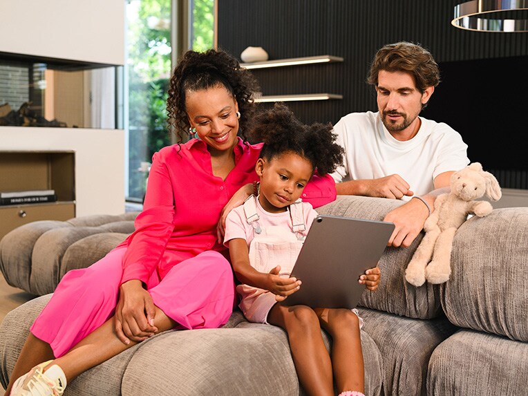Two people and a child sitting and looking at a mobile device together