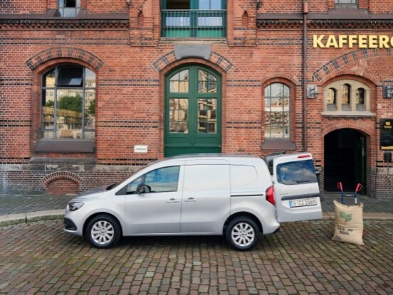 A Mercedes-Benz Citan Panel Van, standing in front of a brick building with the rear door open..