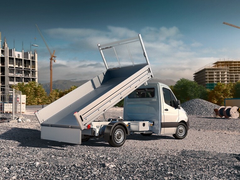 A Mercedes-Benz Sprinter Dropside parked with its flatbed raised in the middle of a construction site.