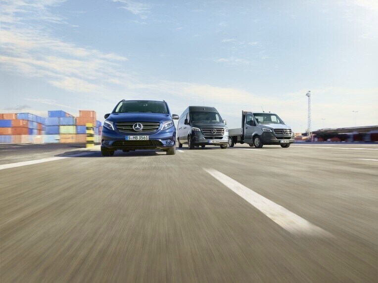 Mercedes-Benz Vito and Sprinter vans on the move on a road with shipping containers in the background.