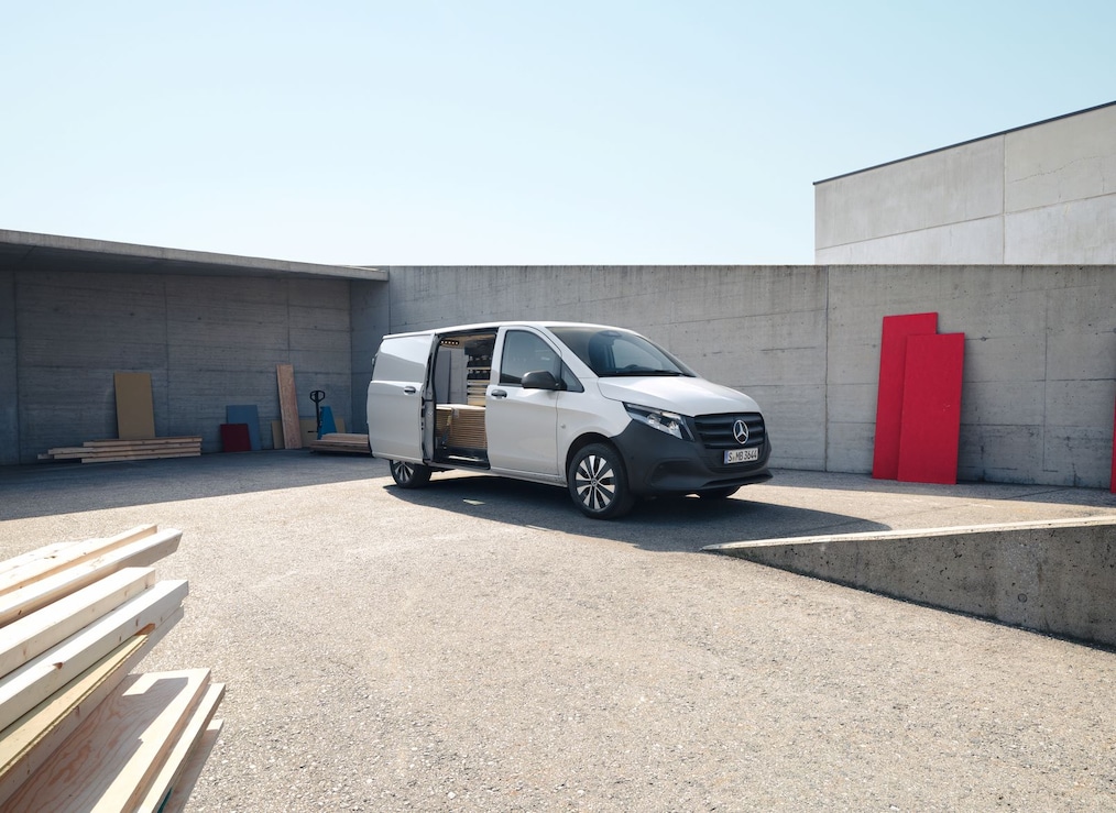The Vito Panel Van in an industrial area with the sliding door on the driver's right side open. 